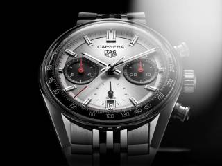 En närbild av en TAG Heuer Carrera herrklocka med en silverfärgad urtavla, röda detaljer och ett stållänkarmband.