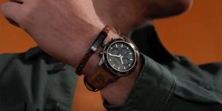 en man i grön skjorta har en timberland klocka med svart urtavla och brunt läderarmband