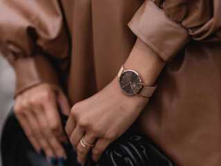 En kvinna som visar upp sina båda händer med en beige klocka från Daniel Wellington.