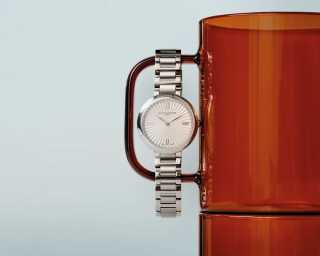 En silverfärgad damklocka från Baume & Mercier hänger på en röd mugg