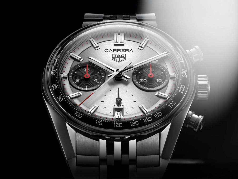 En närbild av en TAG Heuer Carrera herrklocka med en silverfärgad urtavla, röda detaljer och ett stållänkarmband.