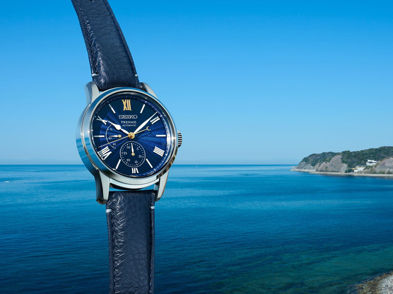 Blå läderrem och urtavla med silver boett klocka mot en blå himmel och hav från Seiko.