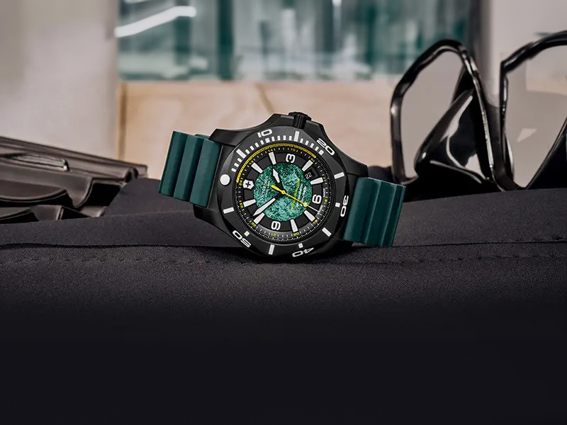 En svart klocka från Victorinox med grön rem och urtavla med en gul sekundvisare.