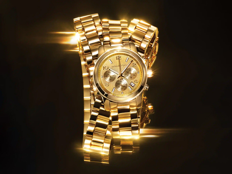 Guldklockor som glänser, där man ser endast en urtavla i guld från Michael Kors med svart bakgrund.