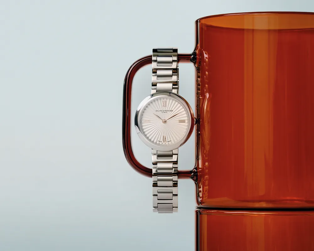En silverfärgad damklocka från Baume & Mercier hänger på en röd mugg