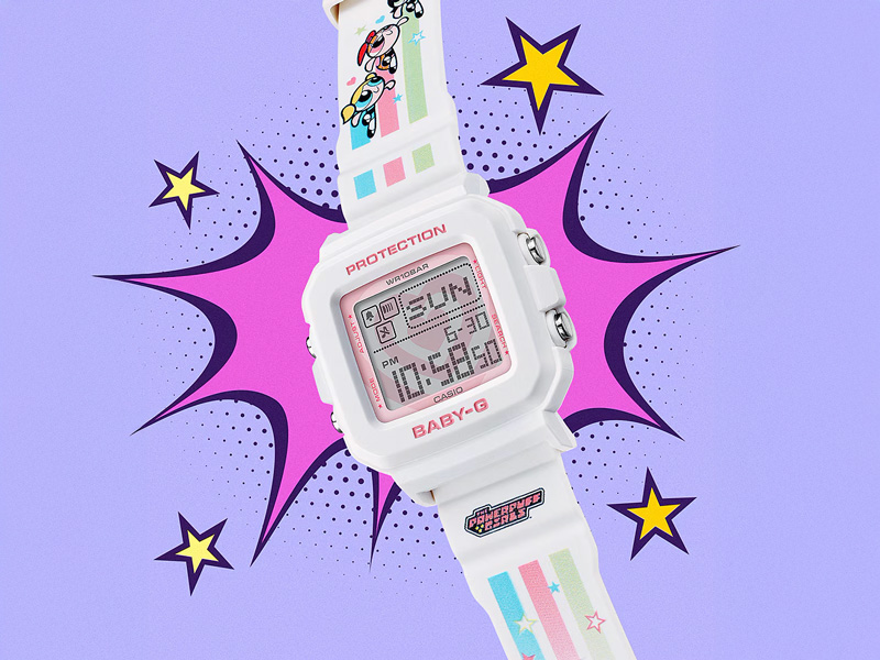 En vit Casio Baby-G klocka med Powerpuff Girls-motiv på armbandet, framför en lila, serietidningsinspirerad bakgrund med gula stjärnor.